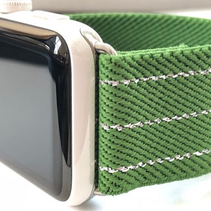 Puede incluir: Una correa de reloj verde con costuras plateadas. La correa est&aacute; hecha de un tejido tejido y tiene una superficie texturizada.
