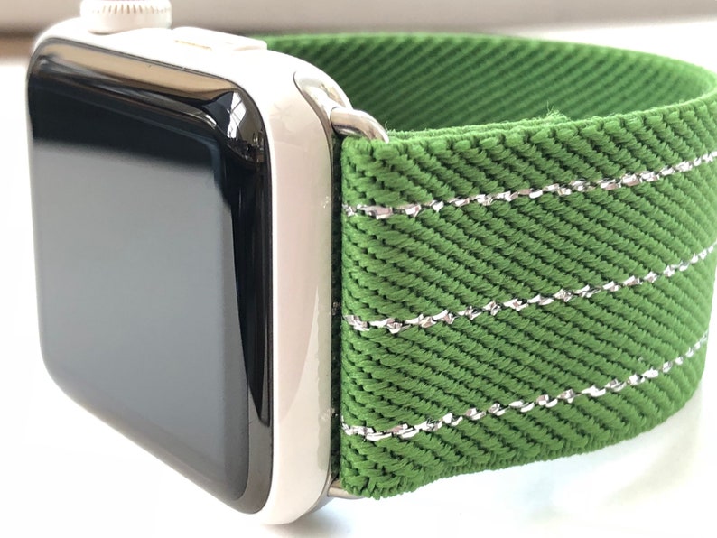 Puede incluir: Una correa de reloj verde con costuras plateadas. La correa est&aacute; hecha de un tejido tejido y tiene una superficie texturizada.