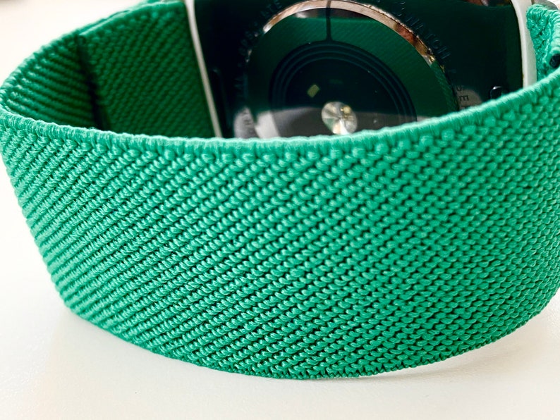 K&ouml;nnte beinhalten: Ein gr&uuml;nes gewebtes Apple Watch Armband mit einem strukturierten Muster.