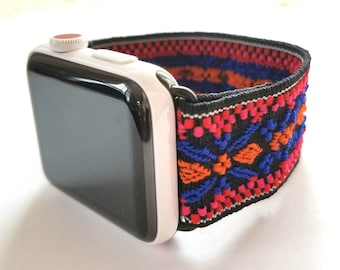 May include: A black Apple Watch band with a colorful geometric pattern. The band is made of a stretchy material and has a red button on the side.