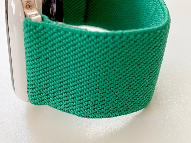 K&ouml;nnte beinhalten: Ein gr&uuml;nes gewebtes Apple Watch Armband mit einer strukturierten Oberfl&auml;che.