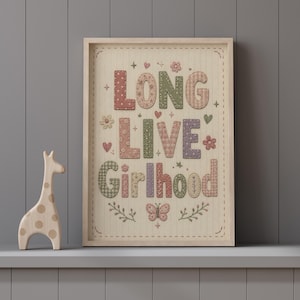 Puede incluir: Un cuadro decorativo con el texto "LONG LIVE Girlhood" en una tipograf&iacute;a estilo patchwork con colores suaves. El dise&ntilde;o incluye patrones florales, de cuadros y lunares con aspecto bordado, adem&aacute;s de corazones, estrellas, flores y una mariposa.
