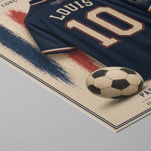 May include: A dark blue sports jersey with the name LOUIS and the number 10 in beige with red outlines, placed on a beige poster featuring a textured blue and red brushstroke design, a soccer ball graphic, and the text PASSION. FIERT&Eacute;. F&Eacute;D&Eacute;RATION FRAN&Ccedil;AISE.