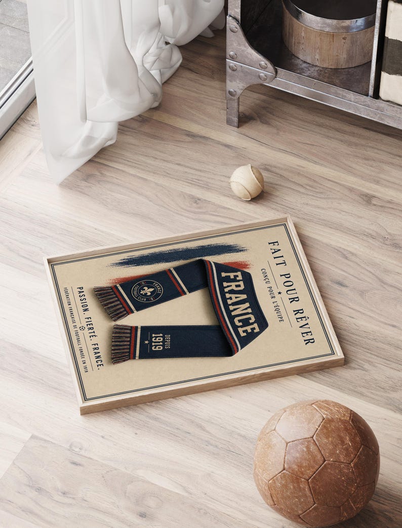 May include: A framed rectangular print featuring a navy blue scarf with red and white stripes, a fleur-de-lis emblem, and the text "FRANCE", "FAIT POUR R&Ecirc;VER", "CON&Ccedil;U POUR L'&Eacute;QUIPE", "PASSION. FIERT&Eacute;. FRANCE.", and "DEPUIS 1919" on a beige background.