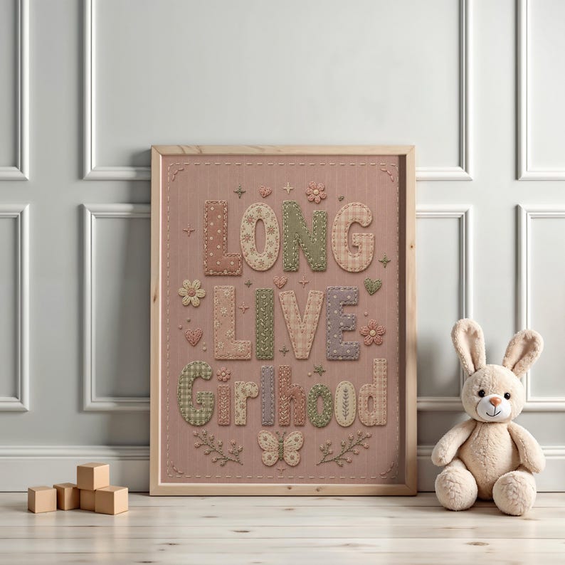 Puede incluir: Una l&aacute;mina enmarcada sobre un fondo rosa empolvado con el texto LONG LIVE GIRLHOOD en letras grandes estilo patchwork con varios patrones como cuadros vichy, flores y lunares, decorado con peque&ntilde;as flores bordadas y una mariposa.
