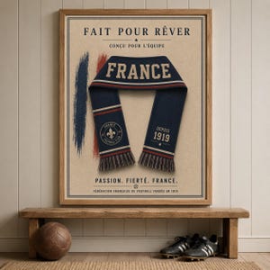May include: A framed poster featuring a navy blue scarf with the word FRANCE, a fleur-de-lis emblem, and the text DEPUIS 1919. The background includes brush strokes in blue, white, and red, with the text FAIT POUR R&Ecirc;VER and PASSION. FIERT&Eacute;. FRANCE.