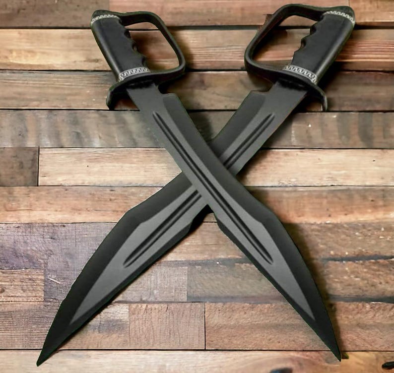 May include: Two black swords with a grey stripe design are crossed against a wooden background. Each sword has a handle with a D-shaped guard and a decorative silver band. The blades are long and pointed.
