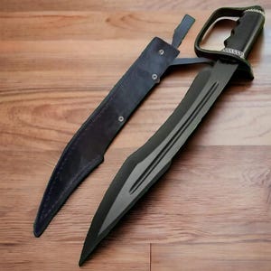 May include: A black sword with a curved blade and a leather sheath. The sword has a distinctive handle with a guard. The sheath is also black and appears to be made of leather. The sword is lying on a wooden surface.