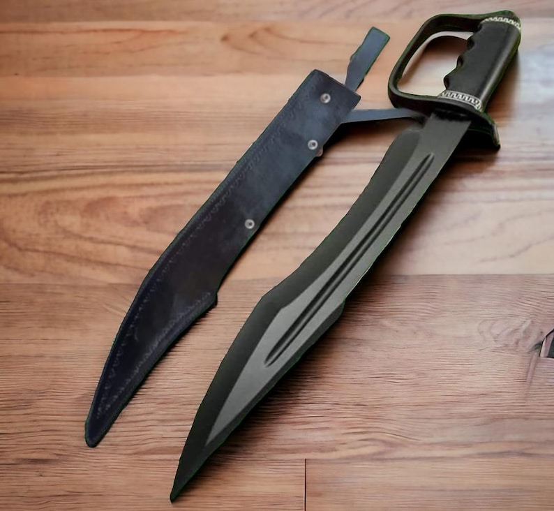 May include: A black sword with a curved blade and a leather sheath. The sword has a distinctive handle with a guard. The sheath is also black and appears to be made of leather. The sword is lying on a wooden surface.
