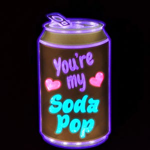 Könnte beinhalten: Ein braunes Design in Form einer Soda-Dose mit dem Text "You're my Soda Pop" in Lila und Türkis. Zwei rosa Herzen sind ebenfalls im Design enthalten. Die Dose hat eine lila Umrandung und einen Aufreißer.