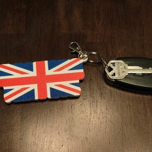 K&ouml;nnte beinhalten: Eine wei&szlig;e Keramik-Tasse mit schwarzem Henkel und dem Text "But First, Coffee" in schwarzer, handschriftlicher Schrift. Die Tasse steht auf einer wei&szlig;en Oberfl&auml;che.