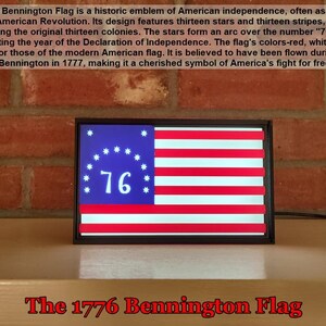 May include: A framed replica of the 1776 Bennington Flag, featuring thirteen white stars in a circle around the number "76" on a blue background. The flag has thirteen alternating red and white stripes.