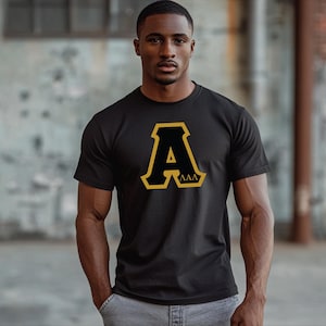 May include: Black t-shirt with a large gold letter "A" with the letters "AAA" inside the "A".