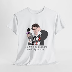 May include: White t-shirt featuring a cartoon illustration of a man holding a microphone and the text "I'm the only one here musically inclined."