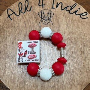 May include: A handmade bracelet with red and white beads, accented with silver-colored spacers. A small rectangular charm features the Dr. Pepper logo and the phrase "I WILL DRINK Dr. Pepper EVERYWHERE". The bracelet is displayed on a wooden surface with the text "All 4 Indie".