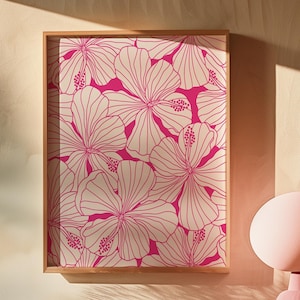 May include: A framed print of a pink floral pattern with white outlines. The flowers are stylized and resemble hibiscus. The print is in a wooden frame.