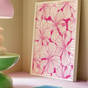 May include: A framed print with a white background and a pink floral pattern. The flowers are stylized and have a graphic design.
