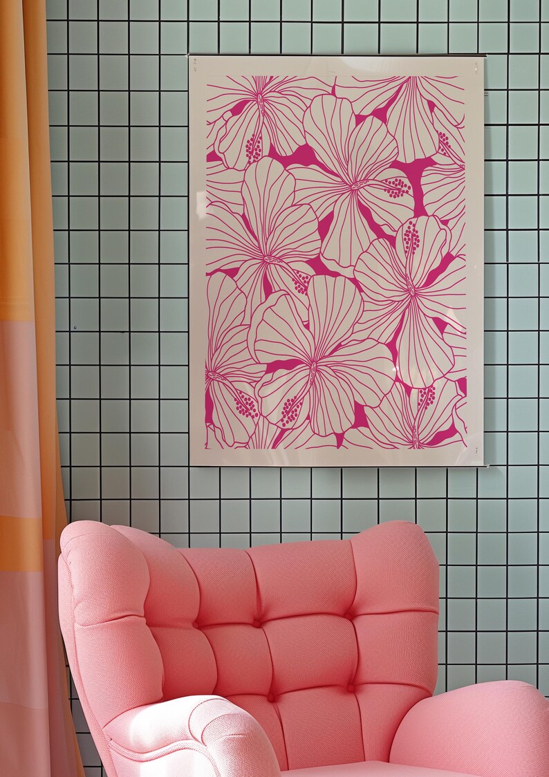 May include: A pink armchair with a tufted back and seat sits in front of a wall with a framed print of pink hibiscus flowers on a white background.