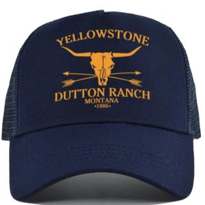 May include: A navy blue trucker hat with a yellow embroidered logo that says "Yellowstone Dutton Ranch Montana *1886*" with a bull skull and arrows.