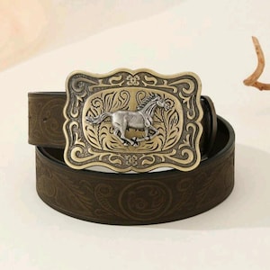 May include: A brown leather belt with an ornate metal buckle featuring a silver horse design. The buckle has a detailed floral pattern.