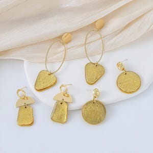 May include: Six pairs of gold-tone earrings with different geometric shapes and textures. The earrings are made of metal and have a gold finish.