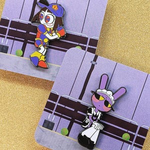 May include: Two enamel pins featuring cartoon characters on display cards. One pin shows a character in a blue baseball cap and colourful athletic gear. The other pin depicts a purple rabbit character wearing a black and white maid outfit.