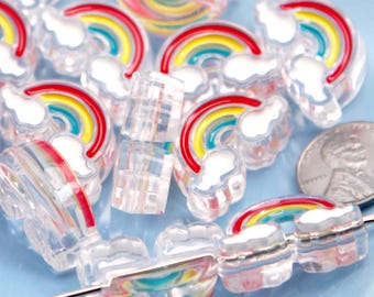 May include: Clear acrylic rainbow and cloud beads with red, yellow, and blue arches. The beads are strung on a needle, and a penny is included for size reference. These beads are ideal for jewelry making and crafts.