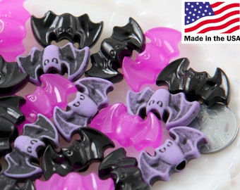 Può includere: Una collezione di bottoni di plastica a forma di pipistrello, di colore viola e nero. I bottoni sono lucidi e hanno un design 3D. Prodotto negli Stati Uniti.
