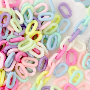 Puede incluir: Un montón de eslabones de cadena de plástico de color pastel. Los eslabones son de forma ovalada y tienen un acabado liso.