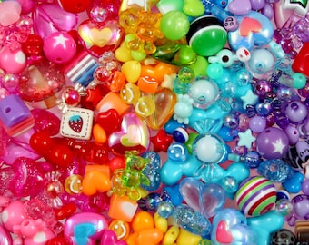 May include: A large assortment of colorful plastic beads in various shapes, including hearts, stars, and smiley faces. The beads are perfect for making jewelry, crafts, and other projects.