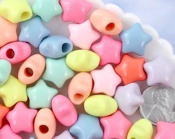 May include: A collection of pastel-colored plastic beads in star and oval shapes. The beads are arranged on a white surface.