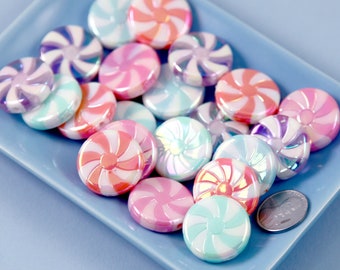Puede incluir: Una colección de cuentas de colores en espiral de bastón de caramelo en tonos de rosa, azul y blanco. Las cuentas son iridiscentes y tienen un acabado brillante.