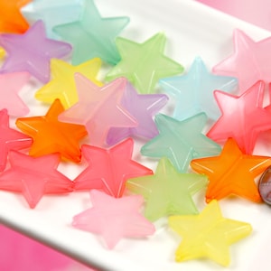 May include: A collection of pastel-colored star-shaped beads. The beads are made of translucent plastic and come in a variety of colors, including pink, blue, green, yellow, and orange.