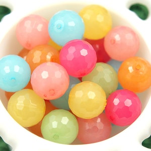 May include: A bowl filled with colourful faceted glass beads in shades of pink, blue, yellow, and orange.
