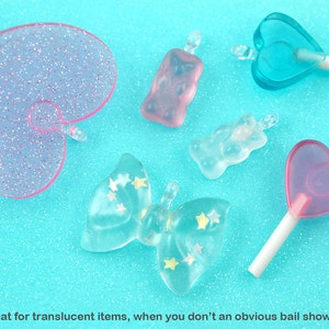 May include: Assortment of translucent pink and blue resin charms in various shapes, including hearts, butterflies, and gummy bears. The charms have a sparkly finish and are perfect for jewelry making or crafting.