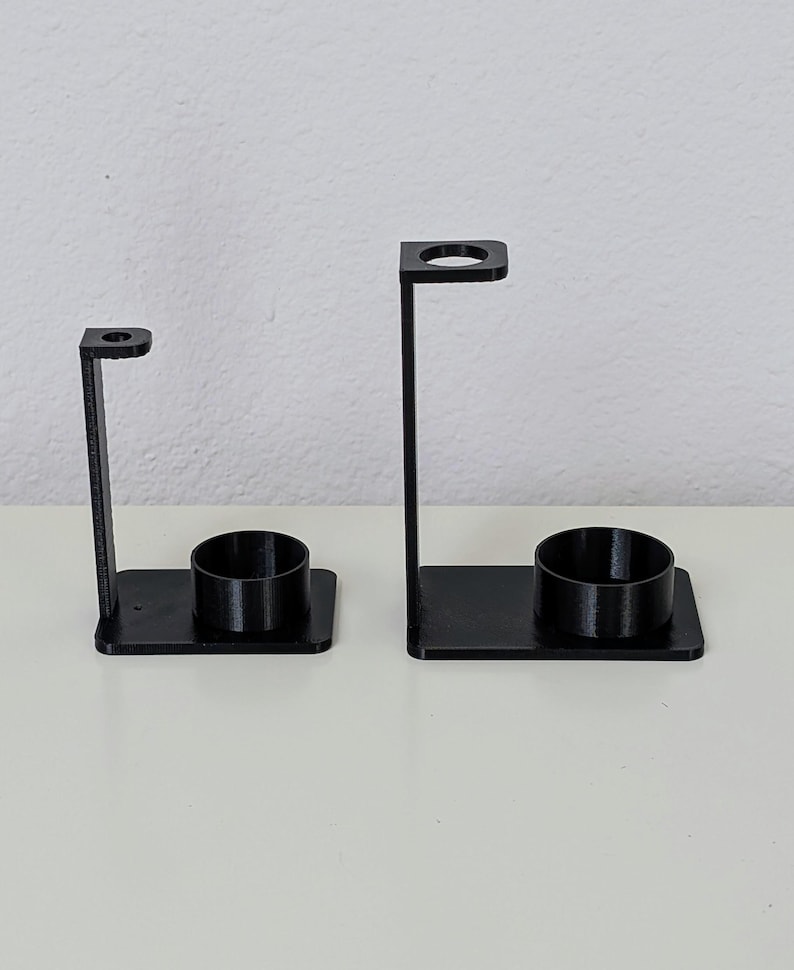May include: Two black plastic toothbrush holders with a round base and a vertical stand with a circular opening at the top.