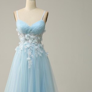 May include: A light blue tulle gown with a sweetheart neckline and floral embellishments around the waist.