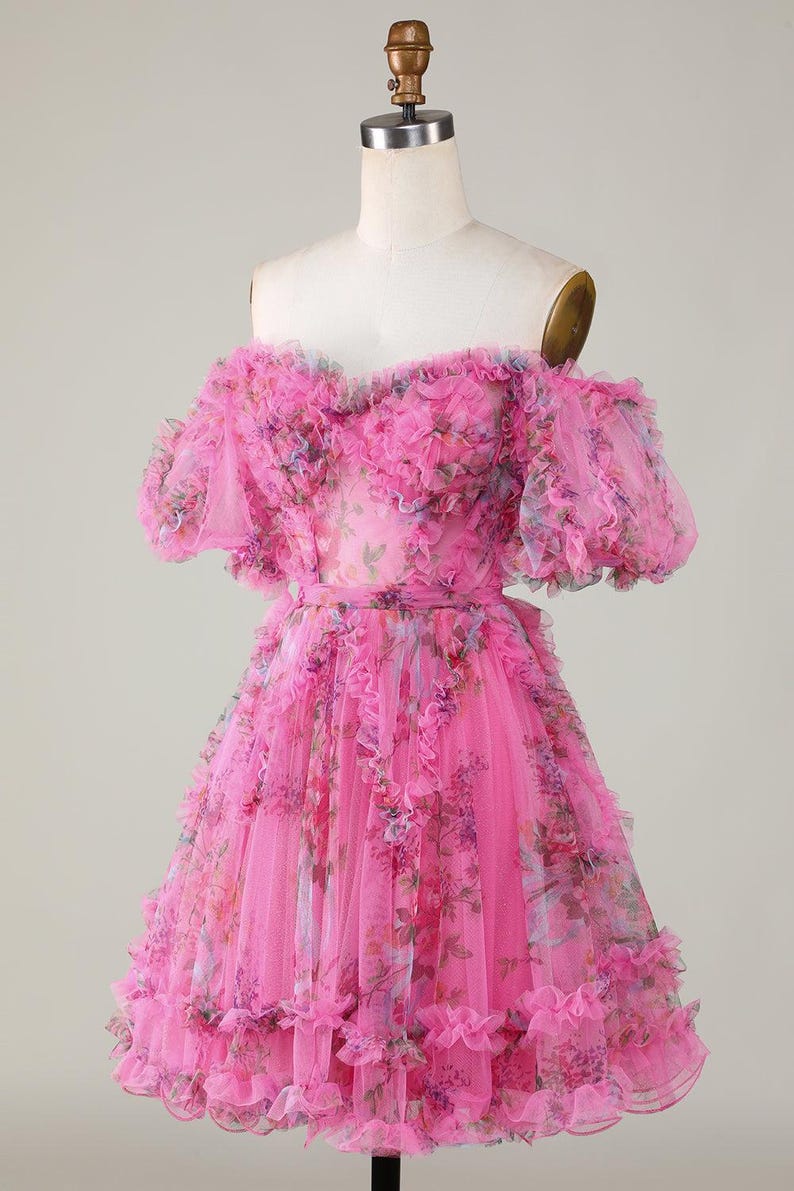 May include: A bright pink, off-the-shoulder dress with a floral design. The dress has layers of ruffled fabric and short sleeves. The bodice and skirt are decorated with a delicate floral print, creating a romantic and feminine appearance.