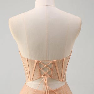 May include: A peach-coloured strapless dress with a lace-up back and a sparkly, tulle skirt.