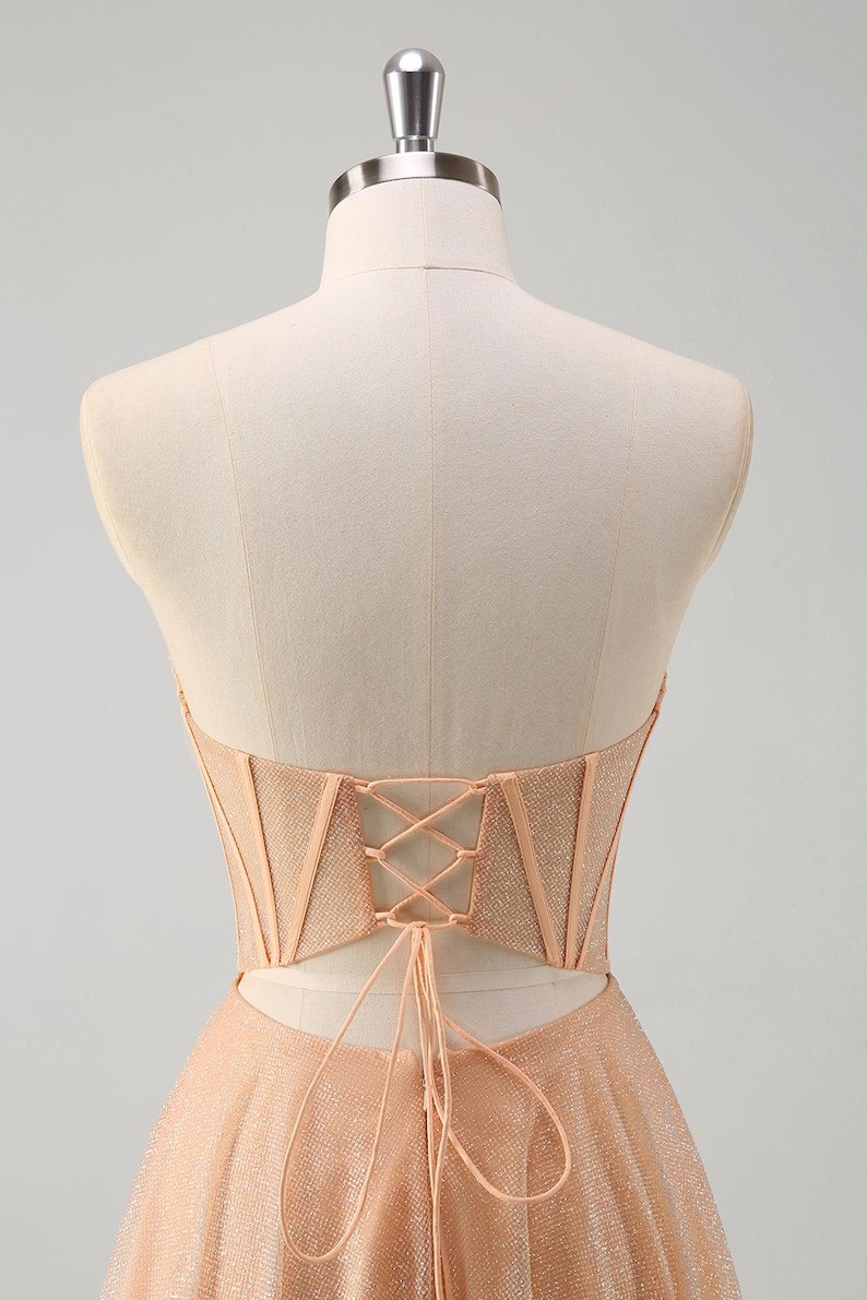 May include: A peach-coloured strapless dress with a lace-up back and a sparkly, tulle skirt.