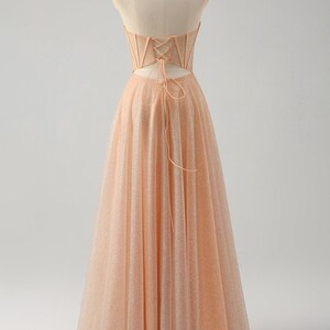 May include: A peach-coloured strapless A-line gown with a lace-up back and a sparkly, tulle skirt.