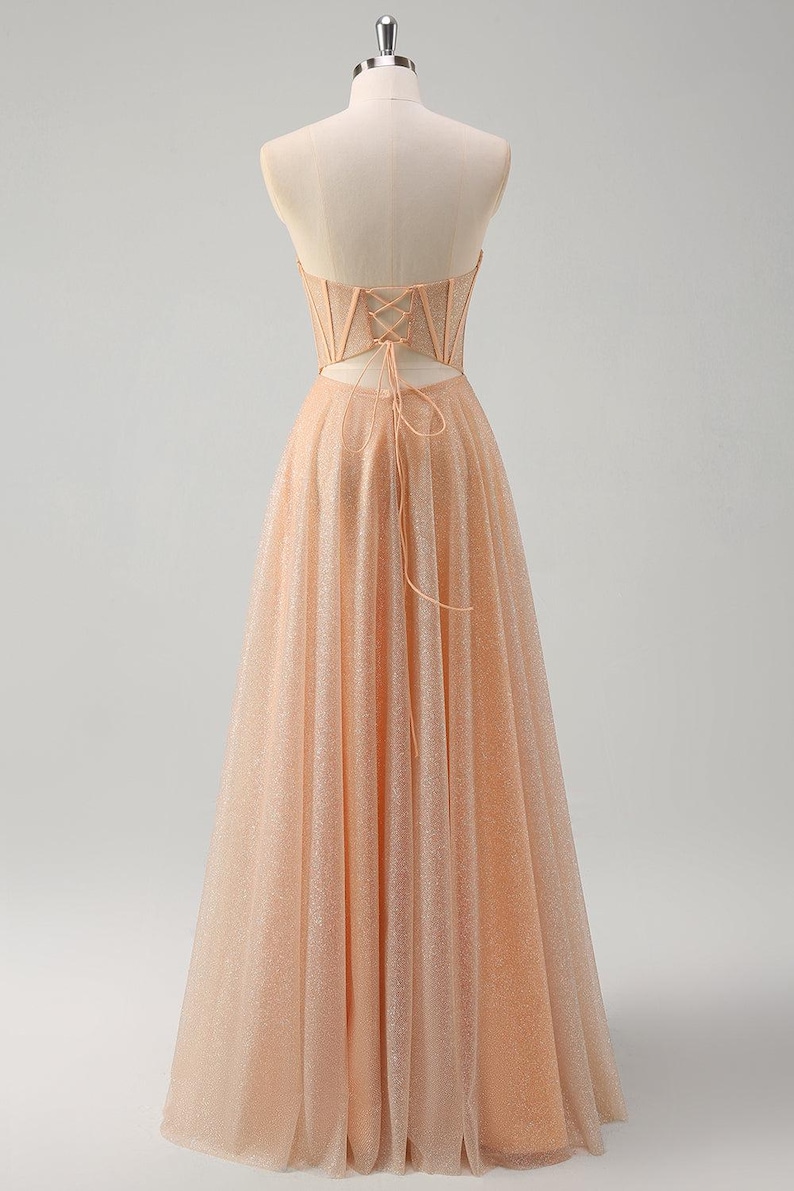 May include: A peach-coloured strapless A-line gown with a lace-up back and a sparkly, tulle skirt.