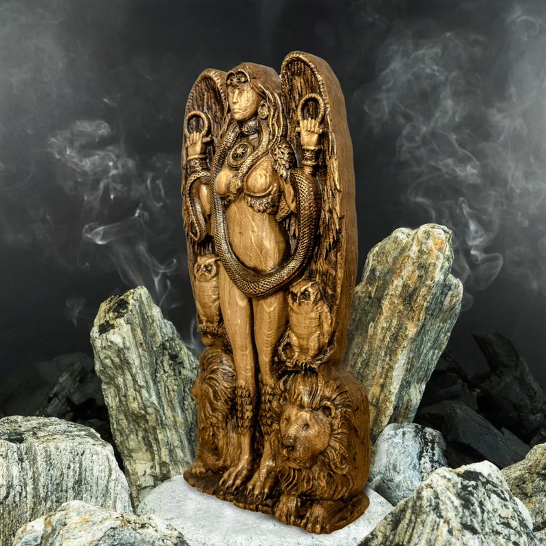 May include: A wooden statue of a goddess with wings, a snake wrapped around her body, and owls and lions at her feet. The statue is painted in a gold color.