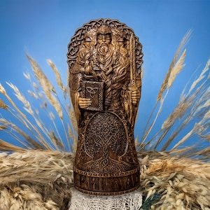 May include: A carved wooden statue depicting a figure with three faces, holding a book and a sword. The statue has detailed carvings, including a tree of life and Celtic knotwork. The colour is a warm brown against a blue backdrop.