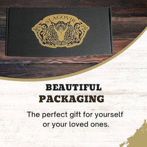 May include: A black box with a gold logo featuring a man with two wolves on either side. The logo says "SLAGOVIR". The box is on a wooden surface. The text "BEAUTIFUL PACKAGING" is below the box. The text "The perfect gift for yourself or your loved ones." is below the text "BEAUTIFUL PACKAGING".