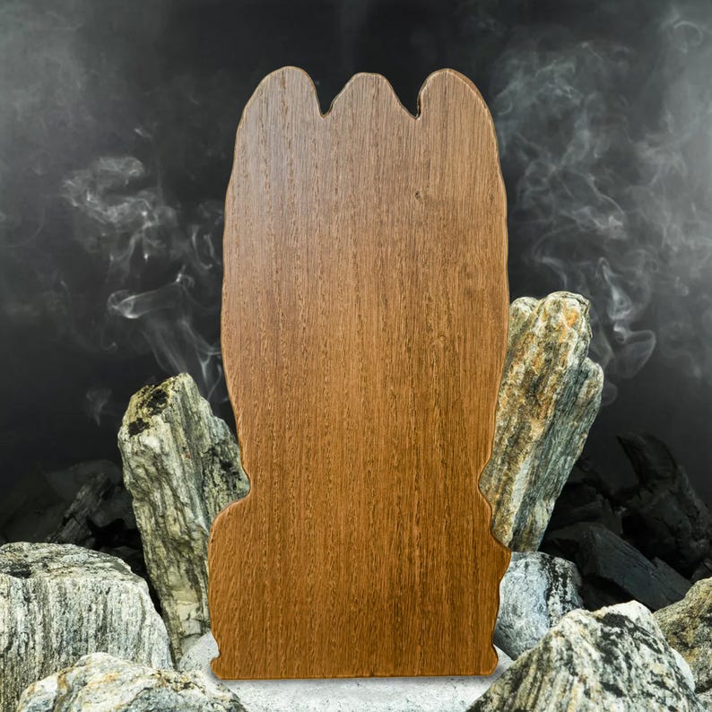 May include: A wooden cutout of a hand with a brown wood grain finish. The cutout is standing on a bed of charcoal and rocks.