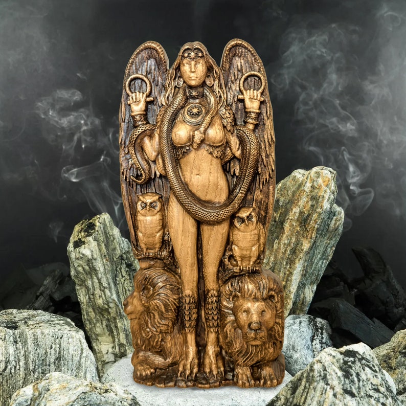 May include: A wooden statue of a female figure with wings, a snake wrapped around her, and two owls perched on her shoulders. The statue is carved with intricate details and has a dark brown finish.