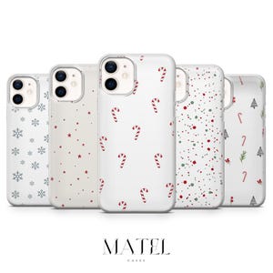 Peut inclure: Cinq coques de téléphone blanches avec des motifs de Noël. Les motifs comprennent des flocons de neige, des étoiles rouges, des cannes en bonbon, des points rouges et des arbres de Noël. La marque "MATEL CASES" est affichée en bas.