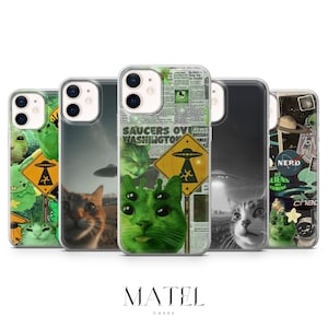 May include: A collection of phone cases featuring cat and alien-themed designs. The cases showcase various graphics, including a green alien cat, a UFO warning sign, and newspaper headlines. The cases are clear with a black border.