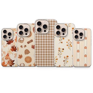 May include: Five smartphone cases arranged in a row, each featuring a distinct autumn-themed pattern. Designs include orange maple leaves, cozy seasonal icons like pies and sweaters, a tan gingham check, delicate wildflowers, and small orange pumpkins.